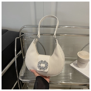 Détail du sac demi-lune plissé blanc avec une grande boucle en strass scintillante