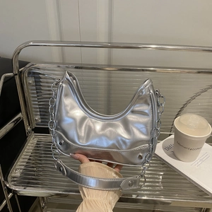 Silver metallic crescent underarm bag with thick chain strap and sleek minimalist design