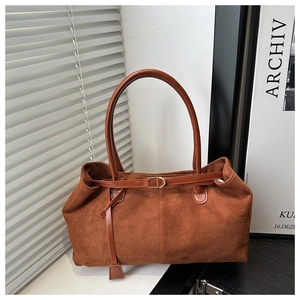 Detail view of large reddish-brown suede tote bag with leather straps and metal buckle