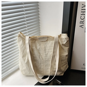 Gros plan détaillé du sac cabas blanc crème avec texture plissée et écusson en cuir
