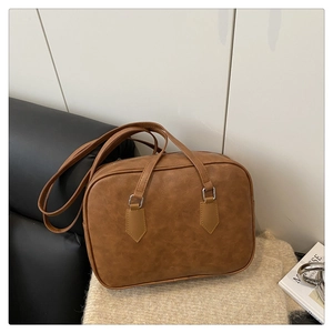 Macro detail of brown vintage faux leather texture and metallic buckle on a Boston bag