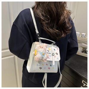 Rear view of model wearing white PU leather backpack with print and plush bear charm