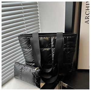 Détail du sac fourre-tout matelassé noir et de sa pochette assortie avec texture à carreaux