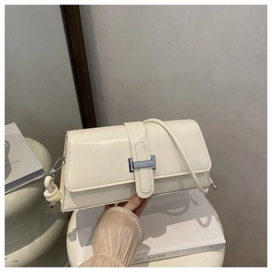 Detail of cream PU leather shoulder bag featuring a silver H-buckle and knotted strap