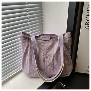 Détail d'un grand sac cabas en nylon lilas avec étiquette logo 'FASHION' en cuir