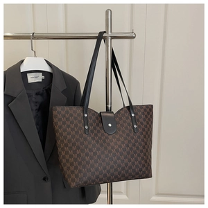 Detail view of large tote bag with M-letter monogram and silver rivet decorations