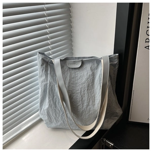 Détail du sac cabas bleu clair en tissu froissé avec étiquette en cuir FASHION