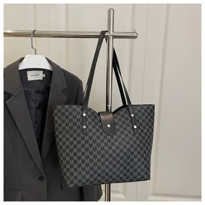 Detailed view of tote bag with M-pattern print, leather straps and silver rivet accents