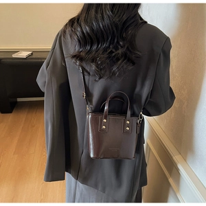 Detailed view of coffee brown crossbody bucket bag with adjustable shoulder strap