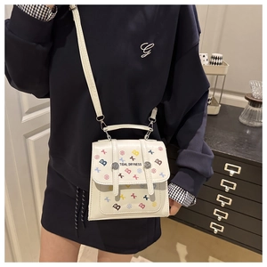 Close-up of white PU leather bag with colorful letter prints and dual buckle closure