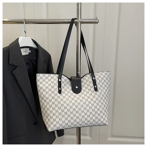 Detail of monogram tote bag with grey M patterns and a sleek black buckle closure