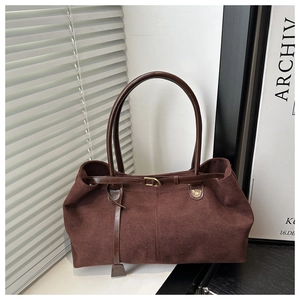 Detail of vintage brown suede tote bag with slim handles and decorative leather strap