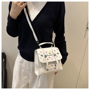Close-up of white crossbody bag with graffiti print and silver twist-lock closure