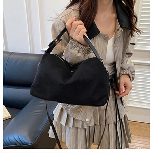Detail of matte black faux suede tote bag featuring leather handles and pleated design