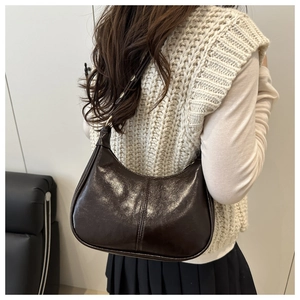 Deep brown glossy hobo bag with adjustable silver buckle strap shown on a model