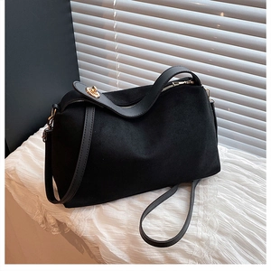 Detailed view of black faux suede tote bag with golden twist lock and leather handle