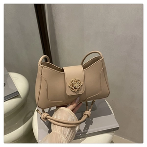 Détail du sac à bandoulière en cuir beige avec boucle fleurie dorée et bandoulière nouée