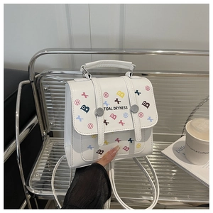 Close-up of a white leather backpack featuring colorful letter prints on a metal chair