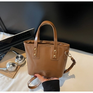 Detail of caramel brown leather handbag with gold rivets and fashion brand lettering