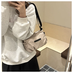Detail of beige nylon crossbody bag with pleated design and adjustable black strap