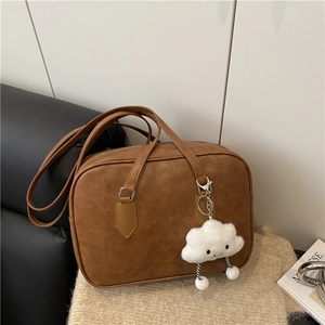 Brown leather Boston handbag with plush charm and long handles for women's daily commute