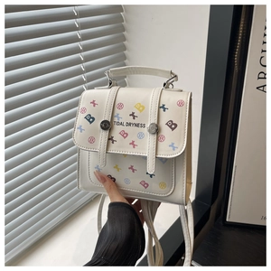 Close-up of white leather backpack with colorful letter B print and metal buckle straps