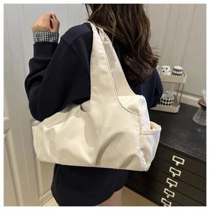Vue latérale d'un sac cabas en nylon ivoire avec poches latérales et design plissé