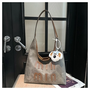 Detail of grey washed canvas hobo bag with leather letter patches and plush puppy charm