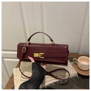 Detailed close-up of dark red crocodile embossed faux leather bag with gold buckle clasp