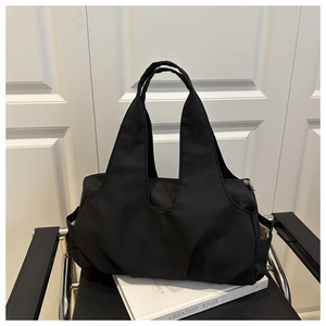 Gros plan d'un grand sac cabas en nylon noir avec poches latérales sur un livre blanc