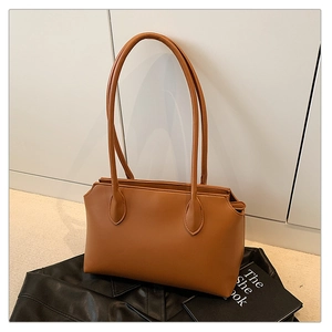 Detail of a minimalist brown leather tote bag with slim shoulder straps for daily use
