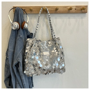 Close-up of silver sequin tote bag hanging on a wooden hanger with fashion accessories