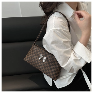 Detail shot of the retro brown leather shoulder bag featuring a silver metal bow accent