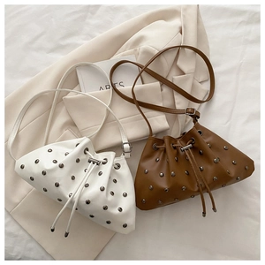 Detail of drawstring bucket bags with rivets in beige and brown PU leather texture