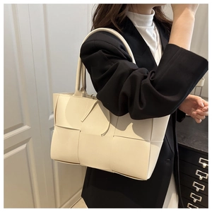 Detail of cream woven tote bag showing wide faux leather strips and minimalist stitching