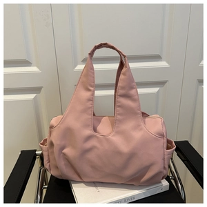 Détail du sac cabas en nylon rose bouffant avec large bandoulière posé sur un livre blanc