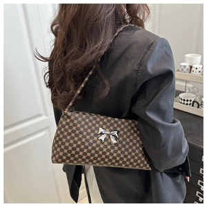 Detail of monogram shoulder bag with silver bow accent on black blazer outfit