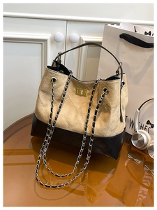 Detail of two-tone stitching, quilted leather texture and gold metal clasp on handbag