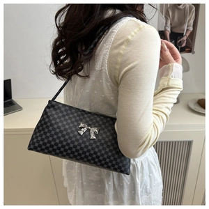 Chic black shoulder bag with geometric print and silver bow detail on a casual model