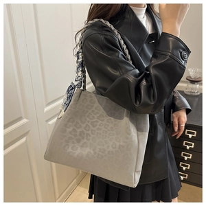 Detailed view of grey leopard print tote bag with woven handles and floral scarf detail