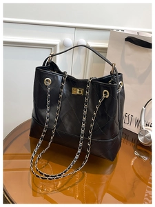 Detail of black quilted leather tote with gold chain strap and metallic twist-lock closure