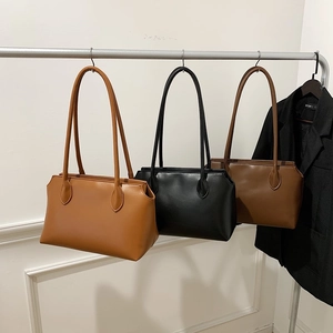 Minimalist leather tote bags in tan, black, and brown hanging in a modern showroom display