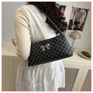 Detail of black monogram baguette bag with silver bow buckle worn by model