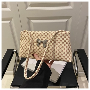 Detail showing cream leather shoulder bag with reddish geometric patterns and silver bow