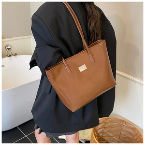 Detailed side view of large dark brown patent leather tote bag with silver hardware charm