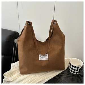 Macro detail of brown faux suede tote bag with Fashion patch and metal eyelet accents