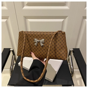 Detail of vintage brown shoulder bag with monogram leather and silver bow buckle