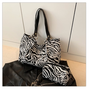 Detail view of zebra print tote bag set with black leather straps and gold hardware