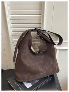 Gros plan sur la texture du sac cabas marron mat et le logo sur le côté en intérieur