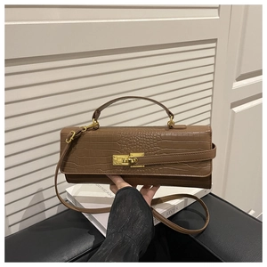 Detailed view of brown crocodile texture leather handbag with golden metal buckle and strap
